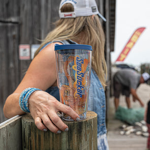 This cup fits in the hand like an old friend. The photo shows a side-view shot of the item, highlighting the vibrant colors of the orange octopus splashing in a bright blue wave, all on the clear plastic material from which the cup is made. Topping it off, literally, is a navy-blue lid that snugly secures the liquid in the vessel.
